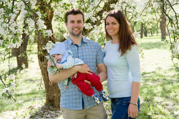 Unga lyckliga familjen promenader utomhus. Föräldrar håller barnet på händer och glädjas. De är lyckliga tillsammans. Leende varandra — Stockfoto