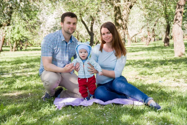 Junge glückliche Familie beim Wandern im Freien. Eltern halten Kind an Händen und freuen sich. Sie sind glücklich miteinander. lächeln einander an — Stockfoto