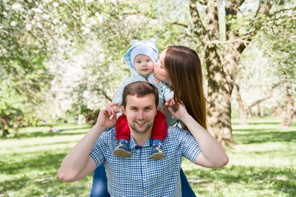 Junge glückliche Familie beim Wandern im Freien. Eltern halten Kind an Händen und freuen sich. Sie sind glücklich miteinander. lächeln einander an — Stockfoto