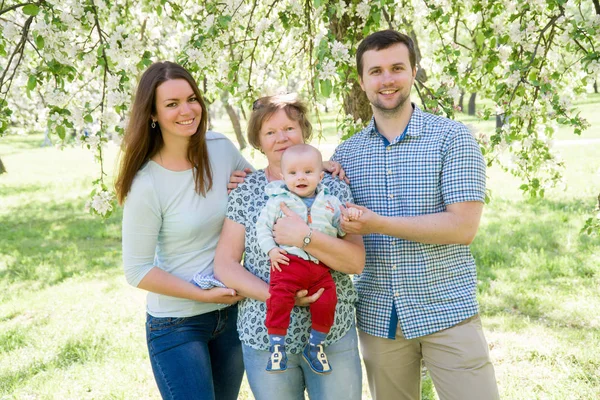 Unga lyckliga familjen promenader utomhus. Föräldrar håller barnet på händer och glädjas. De är lyckliga tillsammans. Leende varandra — Stockfoto