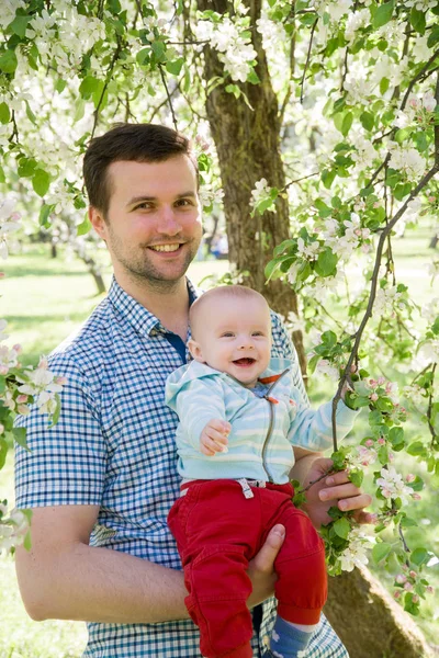 Unga lyckliga familjen promenader utomhus. Far håll barn på händer och glädjas. De är lyckliga tillsammans. Leende varandra. — Stockfoto