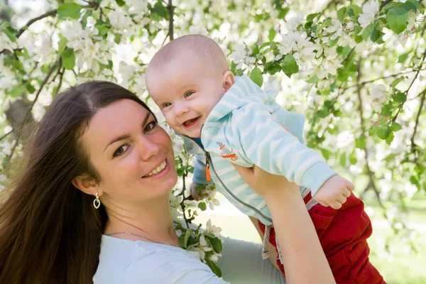 Unga lyckliga familjen promenader utomhus. Mamma håll barn på händer och glädjas. De är lyckliga tillsammans. Leende varandra. — Stockfoto