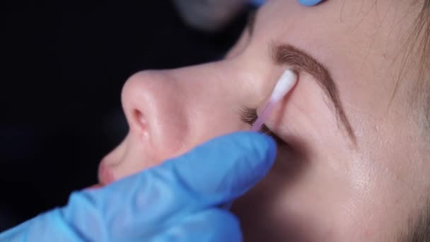 永久性化妆专家在手术前用棉花花蕾擦拭女性患者的脸部。消毒. — 图库视频影像