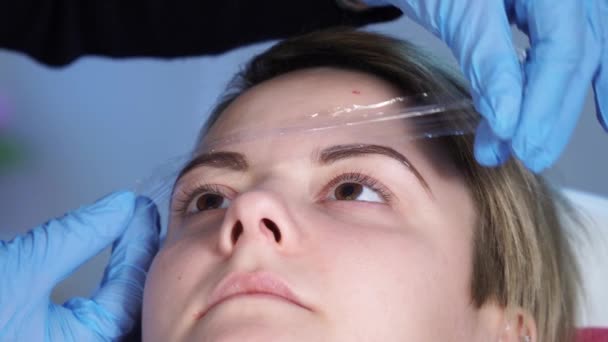 Kosmetikerin, Spezialistin für Permanent-Make-up die Schaffung eines Treibhauseffekts für die schnelle Wirkung der Lokalanästhesie vor der Augenbrauen Permanent-Make-up-Verfahren. Nahaufnahme — Stockvideo