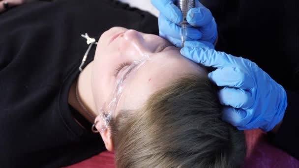 Kosmetolog, specialist på permanent make-up tillämpar lokalbedövning innan förfarandet ögonbryn permanent makeup. närbild. — Stockvideo