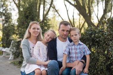 Annem ve babam onların yakışıklı oğlu ve kızı - Park aile ve çocuklar açık havada - genç güzel aile fotoğrafçısına poz ile oynarken