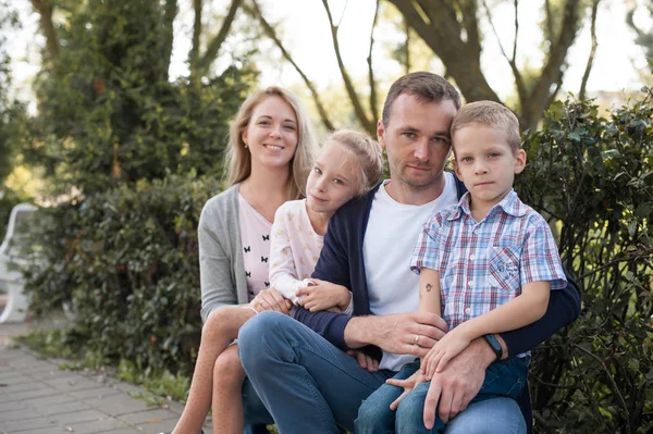 Mama i tata, grając z ich przystojny syn i córka - Rodzina i dzieci na zewnątrz park - młode piękne rodziny pozowanie dla fotografa — Zdjęcie stockowe