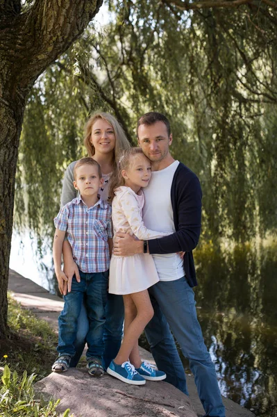 Mama und Papa spielen mit ihrem hübschen Sohn und ihrer Tochter - Familie und Kinder draußen im Park - junge schöne Familie posiert für den Fotografen — Stockfoto