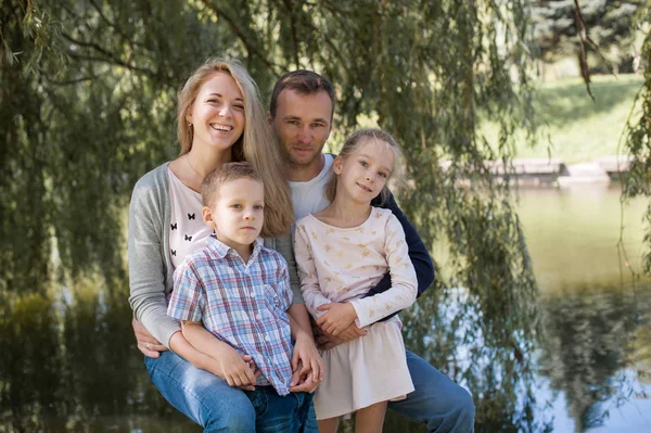 Maman et papa jouent avec leur beau fils et leur belle fille - Famille et enfants à l'extérieur dans le parc - Jeune belle famille posant pour le photographe — Photo