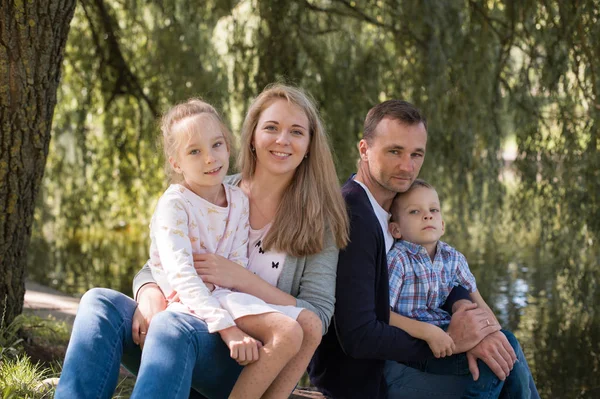 Mama i tata, grając z ich przystojny syn i córka - Rodzina i dzieci na zewnątrz park - młode piękne rodziny pozowanie dla fotografa — Zdjęcie stockowe