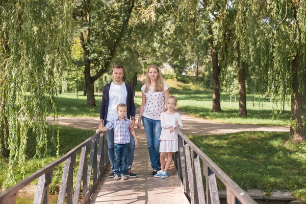 Anya és apa közötti jóképű fia és lánya - család és a gyerekek kint a parkban - fiatal szép család a fotós jelentő játék — Stock Fotó