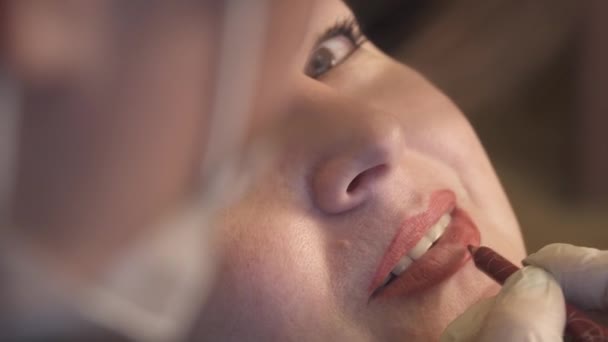 Κοντινό πλάνο. Ειδικός μόνιμο μακιγιάζ εφαρμογή χείλη πριν από τη διαδικασία. Έννοια της ομορφιάς, μακιγιάζ και μόδας — Αρχείο Βίντεο