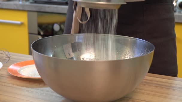 Просіювання борошна в миску на столі на дерев'яному фоні — стокове відео