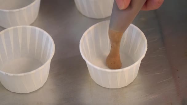 Ponga la masa en vasos de papel. Mano vertiendo masa de pastel en bandeja de magdalenas — Vídeos de Stock