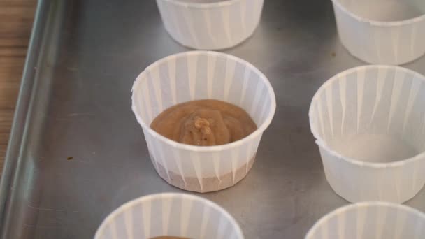 Βάλτε τη ζύμη σε ποτηράκια. Χέρι ρίχνει κέικ ζύμη στην θήκη του muffin — Αρχείο Βίντεο