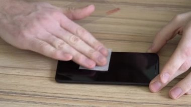 Yakın çekim. Ekranın yeni bir cep telefonu için hazırlanıyor. Nemli bir bezle temizliyor. Yeni koruyucu, doğranmış, darbeye dayanıklı cam.