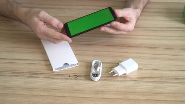 Het uitpakken van een nieuwe mobiele telefoon. Siliconen case, lader, USB-kabel — Stockvideo