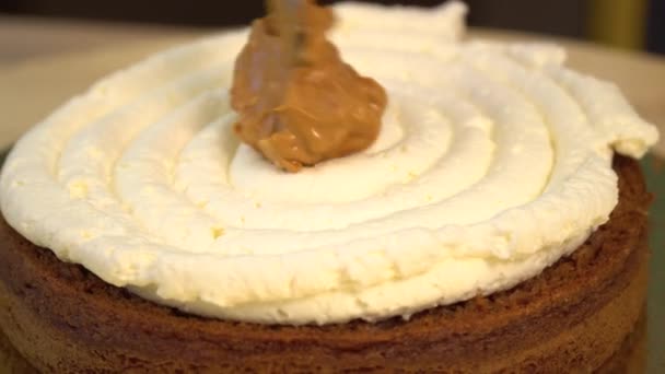 Cake. Brownie. Sweets. Close-up of butter cream on the confection. White gentle cream on a chocolate cake. Close up: delicate cream in a pastry bag. Pastry cream cake is decorated. Sponge cake. — Stock Video