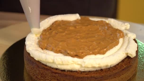 Kek. Brownie. Tatlılar. Tereyağı krema konfeksiyon üzerinde Close-Up. Çikolatalı pasta üzerinde beyaz yumuşak krema. Yakın: hassas krem pasta çantaya. Pasta krem kek dekore edilmiştir. Sünger kek. — Stok video