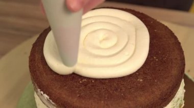 Yakın çekim: bisküvi kremalı kek üzerine bir spiral şeklinde. Çikolatalı krema ile sünger kek. Tatil için yiyecek. Bir şekerci dükkânı pastada hazırlanması.