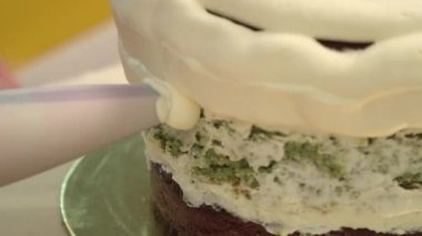 Yakın çekim: bisküvi kremalı kek üzerine bir spiral şeklinde. Çikolatalı krema ile sünger kek. Tatil için yiyecek. Bir şekerci dükkânı pastada hazırlanması.