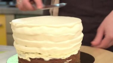 Yakın çekim: bisküvi kremalı kek üzerine bir spiral şeklinde. Çikolatalı krema ile sünger kek. Tatil için yiyecek. Bir şekerci dükkânı pastada hazırlanması.