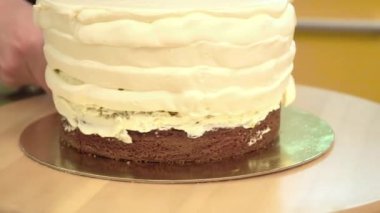 Yakın çekim: bisküvi kremalı kek üzerine bir spiral şeklinde. Çikolatalı krema ile sünger kek. Tatil için yiyecek. Bir şekerci dükkânı pastada hazırlanması.