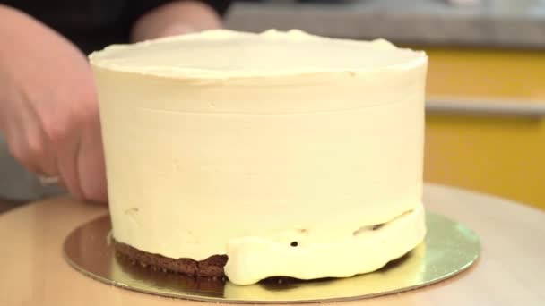 Primo piano: crema di biscotti sotto forma di spirale sulla torta. Pan di Spagna al cioccolato con panna. Il cibo per le vacanze. Preparazione di torta in un negozio di caramelle . — Video Stock