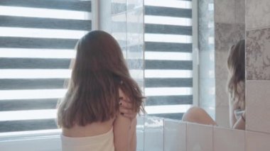 Ayakta, izlemek ve banyo aynada yüzüne kontrol genç güzel kadın