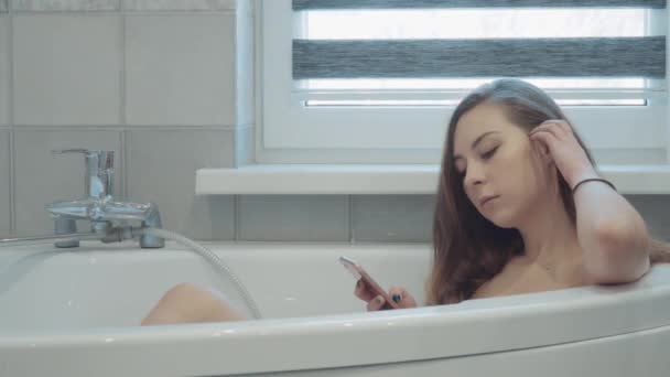Hübsche junge Frau, die im Badezimmer im Handy wedelt — Stockvideo