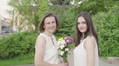 Toplantı kızı ve annesi parkta. Her anne sarılma sevgi ve hassasiyet ile çekici esmer olduğunu