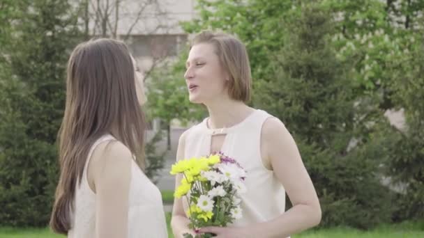 Het meisje geeft bloemen. Een mooie dochter geeft bloemen aan haar moeder — Stockvideo