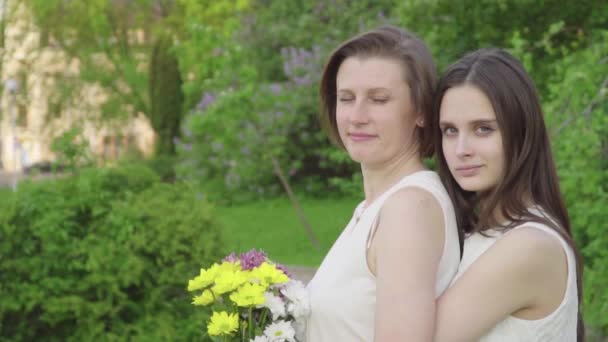 Treffen mit Tochter und Mutter im Park. attraktive Brünette umarmt ihre Mutter mit Liebe und Zärtlichkeit — Stockvideo