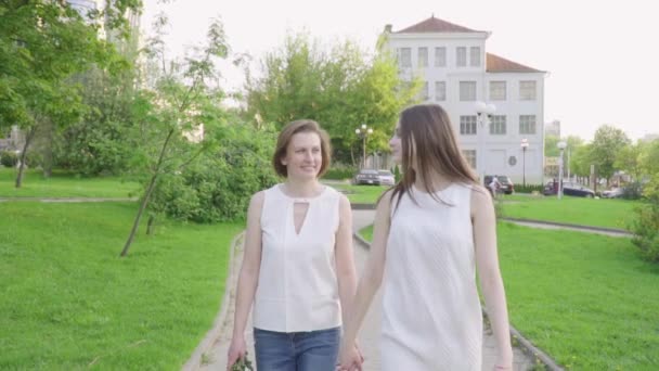 Mujer feliz y su hija pequeña caminando parque. Madre e hija adultas caminando por el parque — Vídeos de Stock