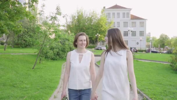 Mujer feliz y su hija pequeña caminando parque. Madre e hija adultas caminando por el parque — Vídeo de stock