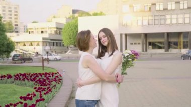 Anne ve gülüyor ve güneşli bir günde parkta sohbet yetişkin kızı. Her anne sarılma sevgi ve hassasiyet ile çekici esmer olduğunu