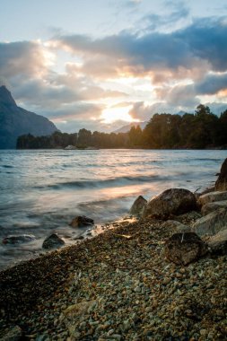 Huechulafquen Gölü üzerinde gün batımı, bulutlu bir öğleden sonra. Junin de los Andes yakınlarında, Neuquen, Arjantin.