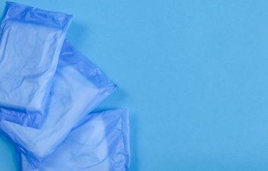 Mavi bir arka plan ve sol altta üç mavi kadın pedi..