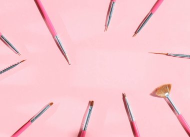 Manikür için fırçalar pembe arka planda daire şeklinde.