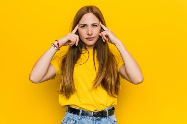 Kızıl saçlı genç kadın bir işe odaklanmış, parmaklarını işaret ediyor..