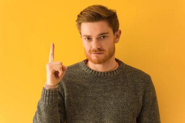 Genç kızıl saçlı adamın yüzü bir numarayı gösteriyor.