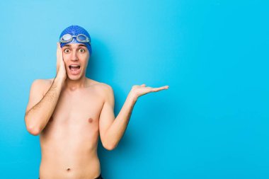 Genç yüzücü avucunun içinde fotokopi alanı tutuyor, el üstünde tutuyor. Şaşırmış ve mutlu..