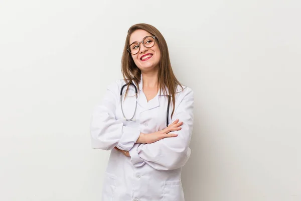 Giovane Donna Medico Contro Muro Bianco Sorridente Fiducioso Con Braccia — Foto Stock