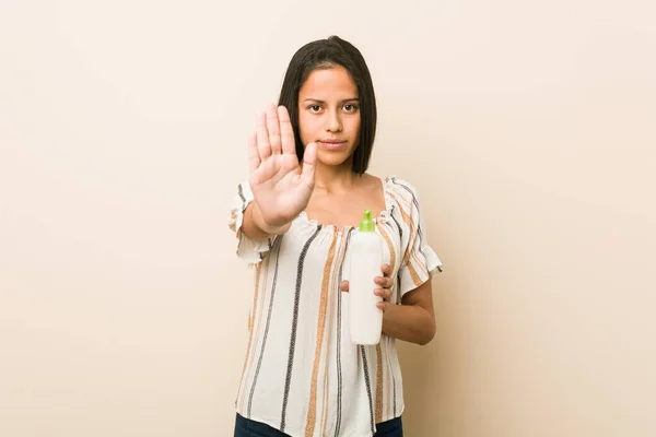 Młoda Latynoska Kobieta Trzyma Butelkę Kremu Stojącą Wyciągniętą Ręką Pokazując — Zdjęcie stockowe