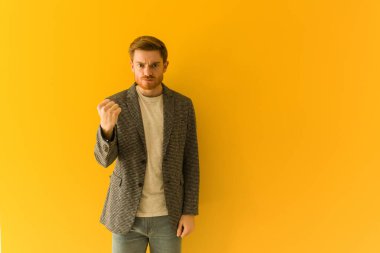 Genç kızıl saçlı iş adamı yumruğunu öne doğru gösteriyor, kızgın bir ifade.