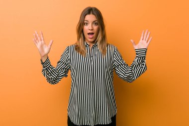 Hoş bir sürpriz alan bir duvara karşı genç otantik karizmatik gerçek insanlar kadın, heyecanlı ve ellerini yükselterek.