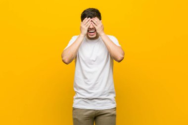 Genç İspanyol rahat adam elleri ile gözleri kapsar, geniş bir sürpriz bekliyor gülümsüyor.