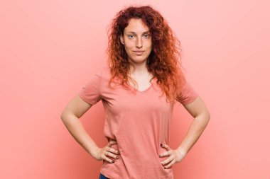 Genç, doğal ve otantik kızıl saçlı kadın ellerini kalçasından ayırmıyor..