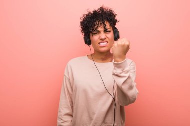 Genç Afrikalı Amerikalı kadın müzik dinliyor kameraya yumruk gösteriyor, agresif yüz ifadesi var..