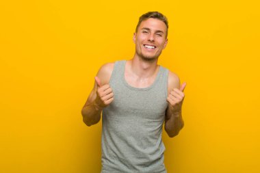 Kafkasyalı genç sporcu iki parmağını da kaldırıyor, gülümsüyor ve kendinden emin..